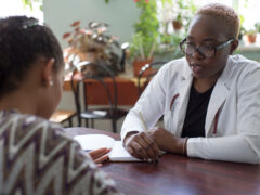 dark-skinned girl, doctor, takes a Latino patient. Doctor and patient of mixed race.