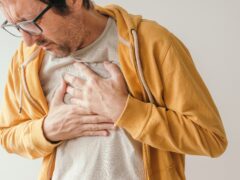 Aching chest, adult male with painful grimace pressing the upper abdomen with his hands to ease pain, pericarditis concept