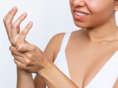 Numbness of the limbs. Pain in the hand, palm and joints. A young woman holding a wrist in her hand isolated on white background. Wrist injuries, carpal tunnel syndrome, neuralgia. Dislocated wrist