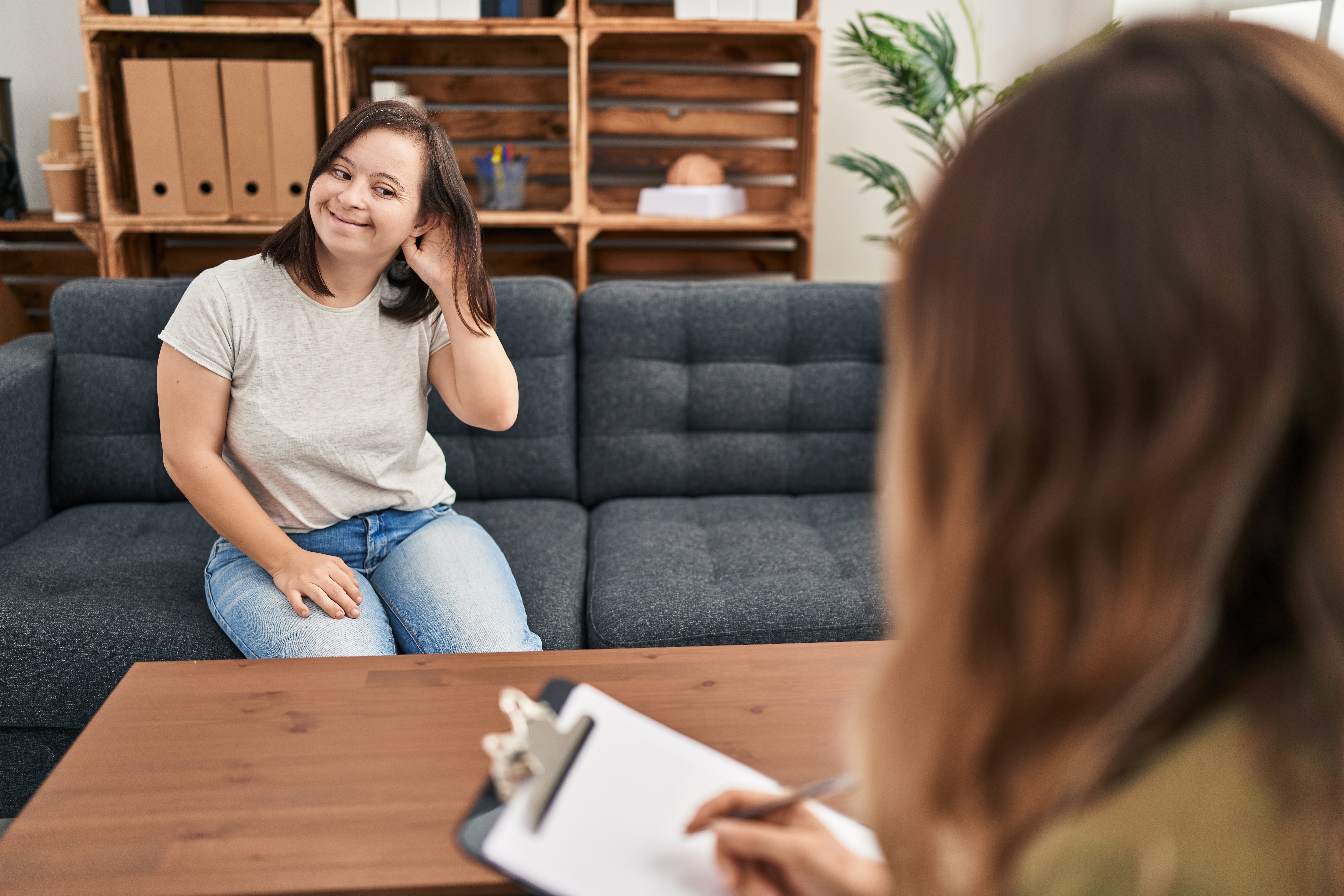 Hispanic girl with down syndrome doing therapy smiling with hand over ear listening an hearing to rumor or gossip. deafness concept.