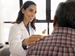 Positive beautiful geriatric medical therapist woman seeing older grey haired patient, touching shoulder od man, giving empathy, support, consultation after treatment, healthcare checkup