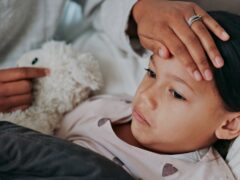 Flu, fever and mother with sick girl for health, virus or infection symptoms in bedroom. Family, childcare and hands of parent with child at home in bed to check temperature for cold, illness and flu