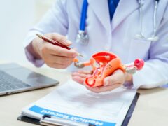 A male doctor wearing glasses sits at a desk in a hospital, discussing a uterus model and women’s health issues like uterine tumors, endometriosis, cervical cancer, and ovarian cancer