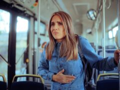 Passenger Suffering from Nausea Standing in a Bus. Stressed woman in painful bellyaches standing in a public transportation vehicle