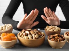 Woman refusing to eat products at grey wooden table, selective focus. Food allergy concept