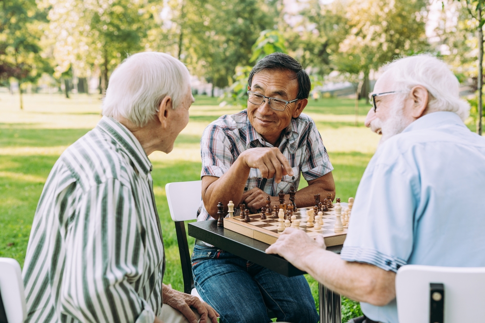 Three men playing chess at a park